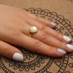 18k-gold-plated-ring-handheld.jpg" alt="Hand holding the 18K Gold Plated Ring showcasing its smooth oval shell centerpiece and shiny gold plating