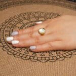 18k-gold-plated-ring-handheld.jpg" alt="Hand holding the 18K Gold Plated Ring showcasing its smooth oval shell centerpiece and shiny gold plating