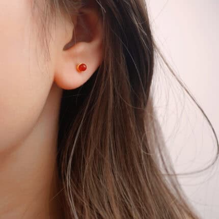 Model wearing carnelian crystal studs, showing warmth and subtle shine