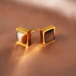 Close-up of tiger eye stones set in square gold-plated frames