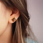 Model wearing the tiger eye square stud earrings, highlighting their size and glow