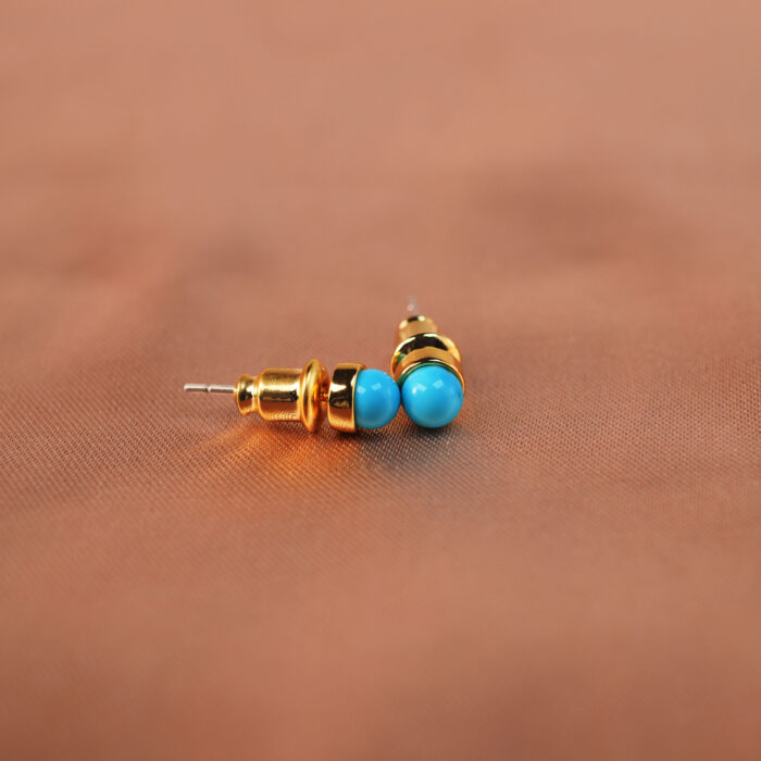 Close-up of turquoise stone set in gold-plated posts showing texture