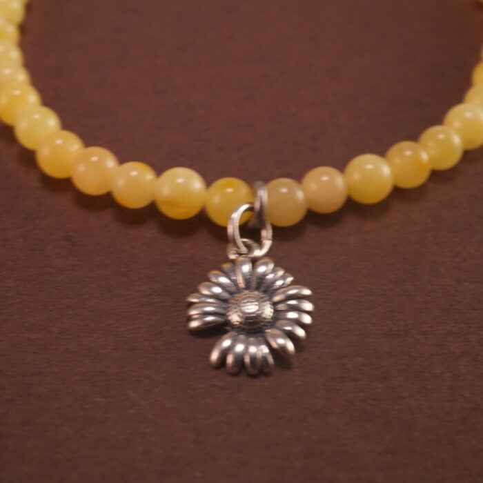 Close-up of amber and aquamarine beads with floral charm and silver accents