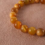 Close-up of 18K gold charm and Tiger Eye bead with polished Citrine stones