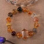 Bracelet placed beside gold coins and natural elements for a wealth theme