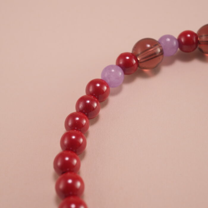 Close-up of rich red cinnabar beads with intricate carving details