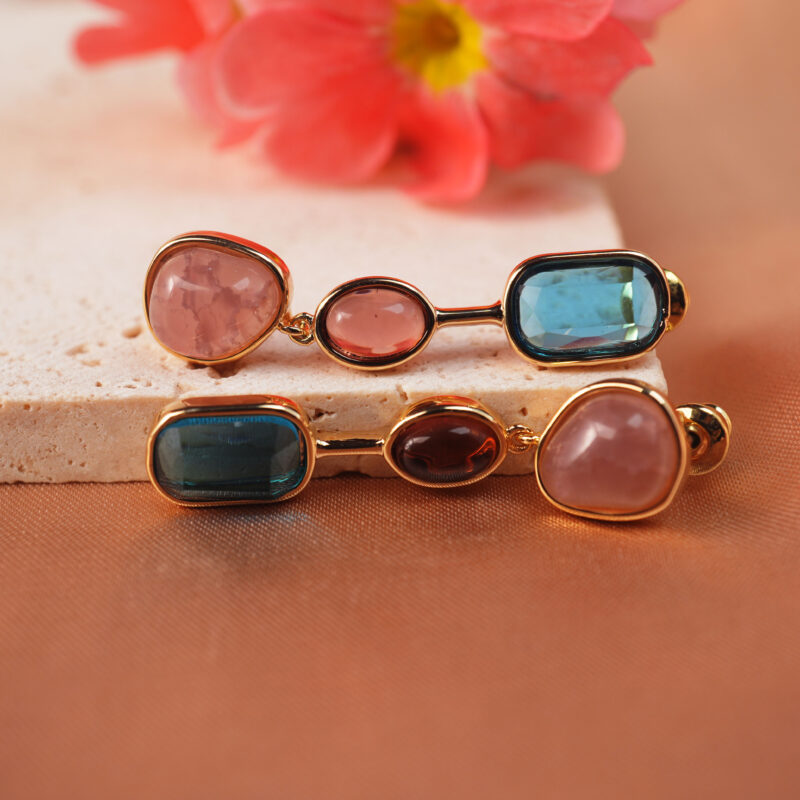 Multi-gemstone dangle earrings with various crystal beads on a light background