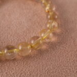 Close-up of golden threads inside rutilated quartz beads and butterfly charm
