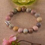 Heart-shaped bracelet placed next to blooming flowers – romantic and elegant handcrafted jewelry setting