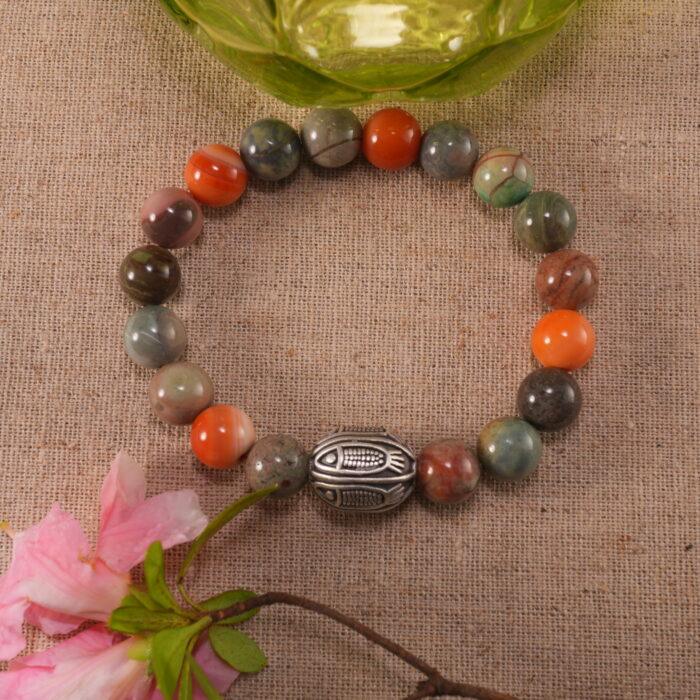 Beaded Alashan stone bracelet beside flowers – calm and grounding jewelry setting