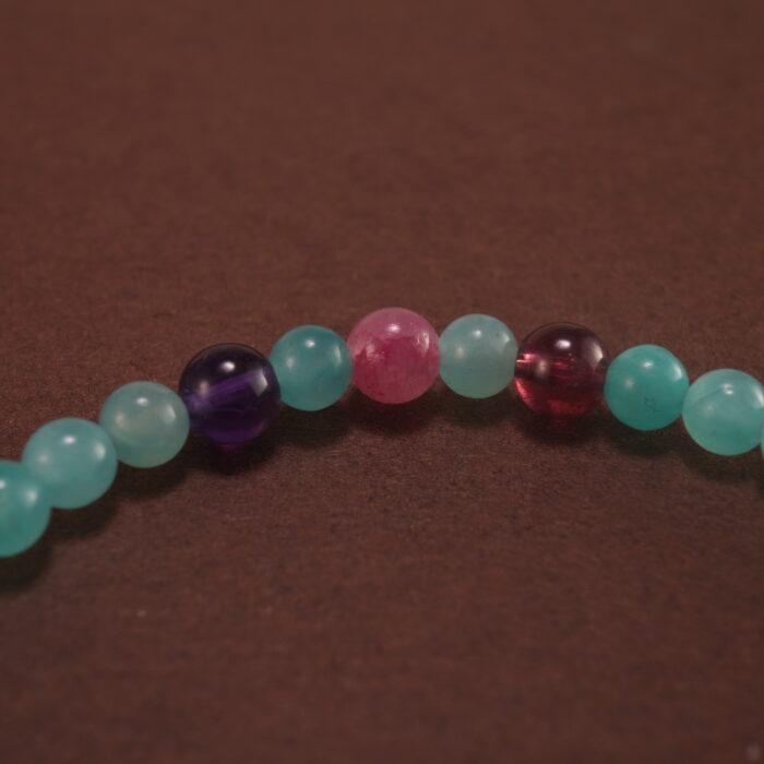 Close-up of Amazonite, Amethyst, Rhodochrosite, and Garnet Beads on Charm Bracelet