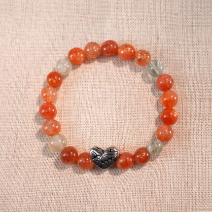 Heart-shaped rutile quartz and Arusha 8mm bracelet on white background