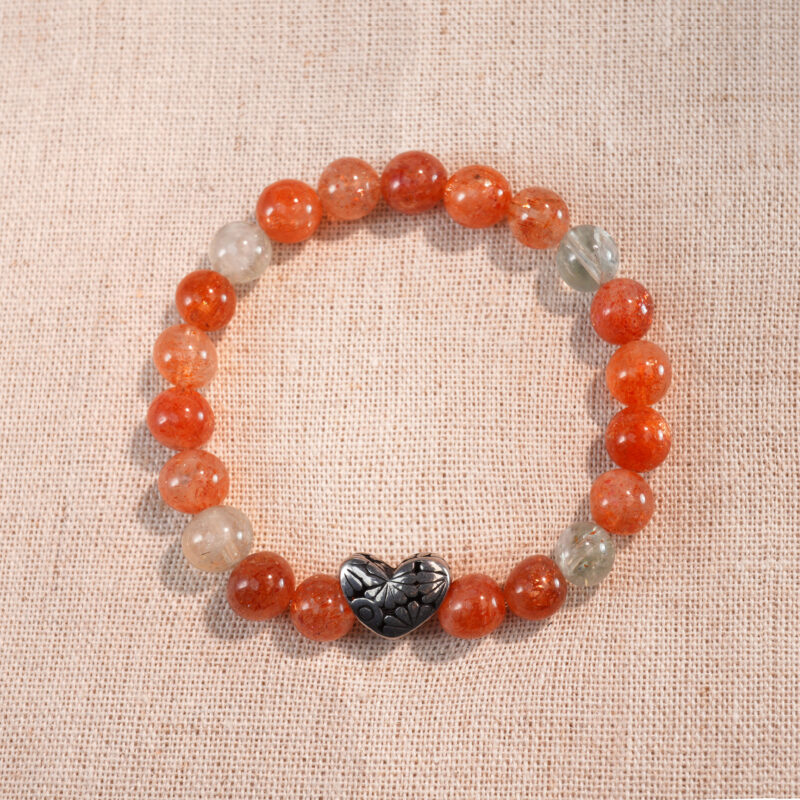 Heart-shaped rutile quartz and Arusha 8mm bracelet on white background