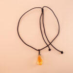 Handmade citrine woven pendant necklace laid on light fabric or stone