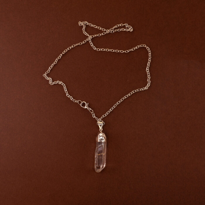 Handmade clear quartz point pendant on light neutral or white background