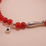 Close-up of red agate 4mm beads and sterling silver accents on energy bracelet
