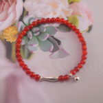 Red agate bracelet placed beside earthy tones and flowers – grounding and energizing