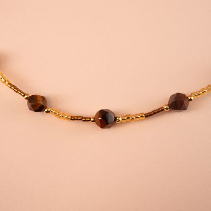 Close-up of faceted tiger eye gemstone beads in a continuous chain