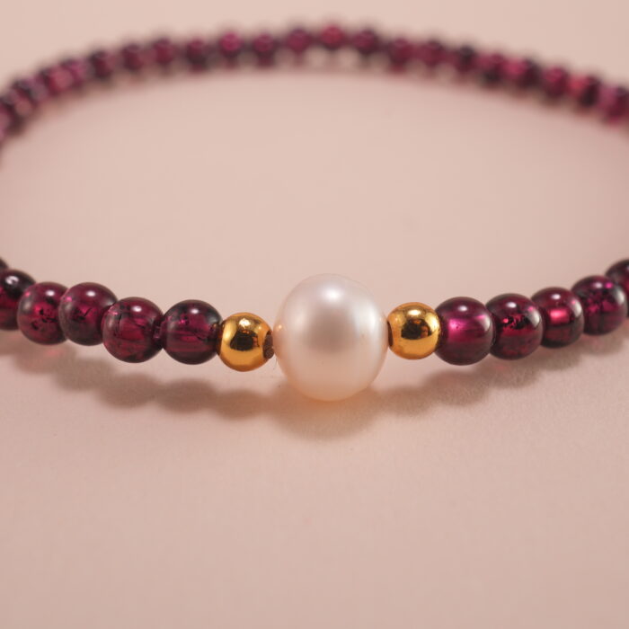 Close-up of garnet and pearl beads strung on elastic cord