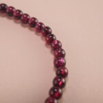 Close-up of garnet and pearl beads strung on elastic cord