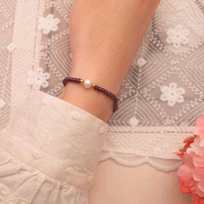 Garnet and pearl bracelet worn on wrist with minimalist outfit