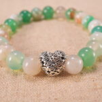 Close-up view of the polished agate beads and heart charm on the bracelet, showing texture and natural color.