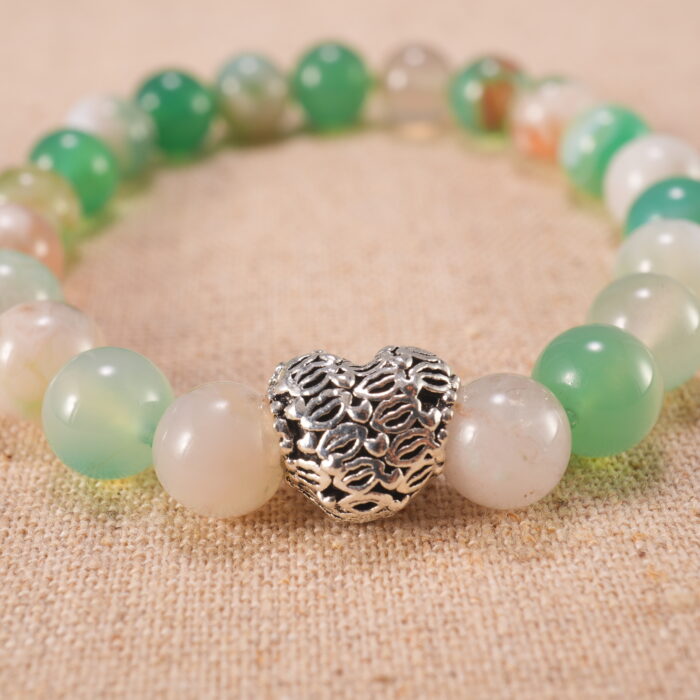 Close-up view of the polished agate beads and heart charm on the bracelet, showing texture and natural color.