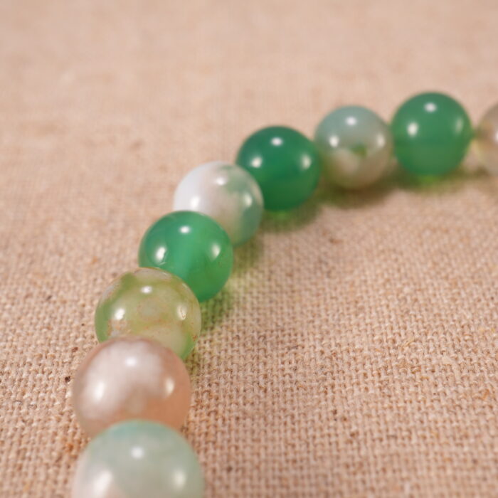 Close-up view of the polished agate beads and heart charm on the bracelet, showing texture and natural color.