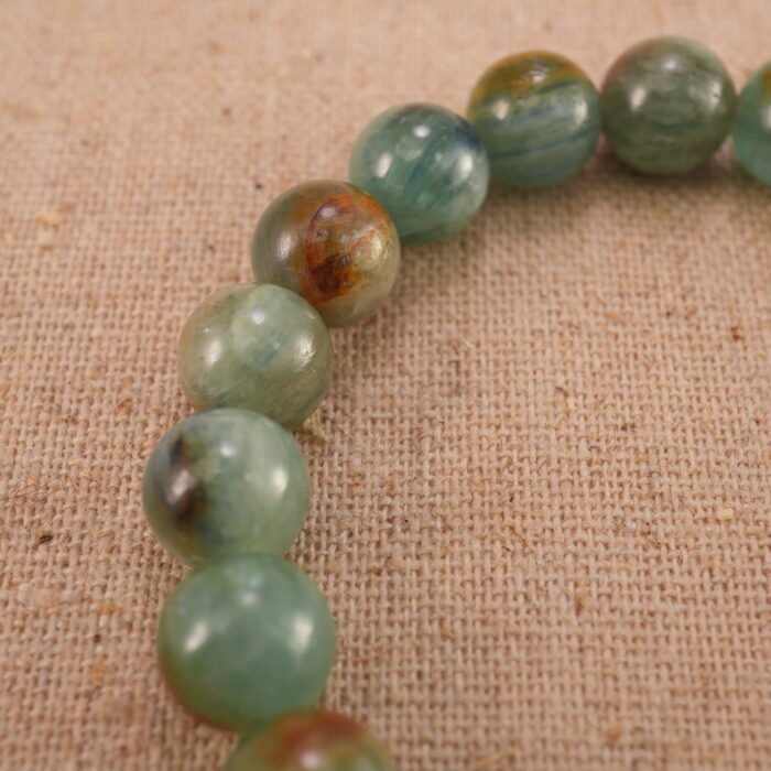 Close-up of the green and cherry blossom agate beads with a delicate heart charm, showing smooth texture and vivid colors.