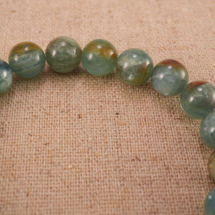 Close-up of the green and cherry blossom agate beads with a delicate heart charm, showing smooth texture and vivid colors.