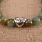 Close-up of the green and cherry blossom agate beads with a delicate heart charm, showing smooth texture and vivid colors.