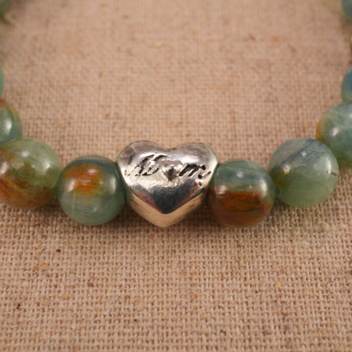 Close-up of the green and cherry blossom agate beads with a delicate heart charm, showing smooth texture and vivid colors.