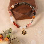 Leo zodiac gemstone bracelet featuring red jasper, crazy lace agate, strawberry quartz, and tiger eye displayed on rustic wooden surface