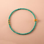 Turquoise beaded bracelet with lucky charm on white background