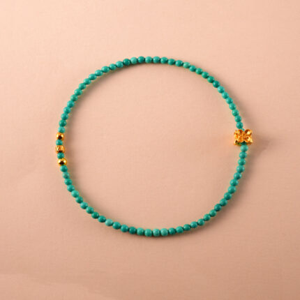 Turquoise beaded bracelet with lucky charm on white background