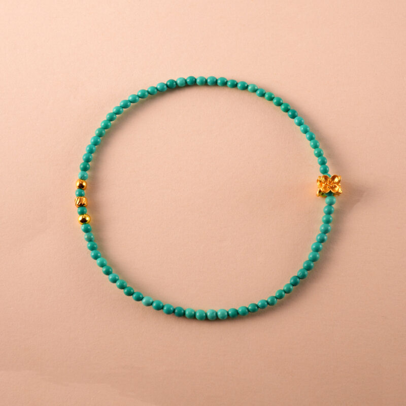 Turquoise beaded bracelet with lucky charm on white background