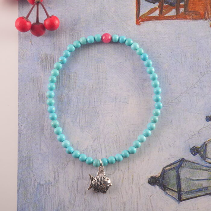 Turquoise and rhodochrosite bracelet placed on natural stone background with soft light