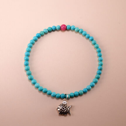 Close-up of a handcrafted turquoise and rhodochrosite bracelet with fish charm on white background