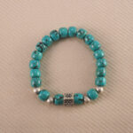 Close-up of an 8mm turquoise gemstone birthstone bracelet on white background