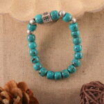 Turquoise birthstone bracelet placed on linen fabric with crystals and soft lighting