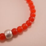 Close-up of small 4mm carnelian and red agate beads with sterling silver accents