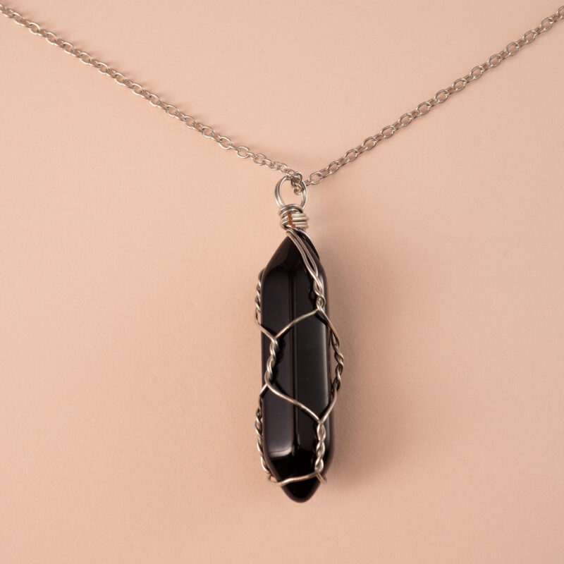 Close-up of pillar-shaped obsidian crystal pendant with silver loop
