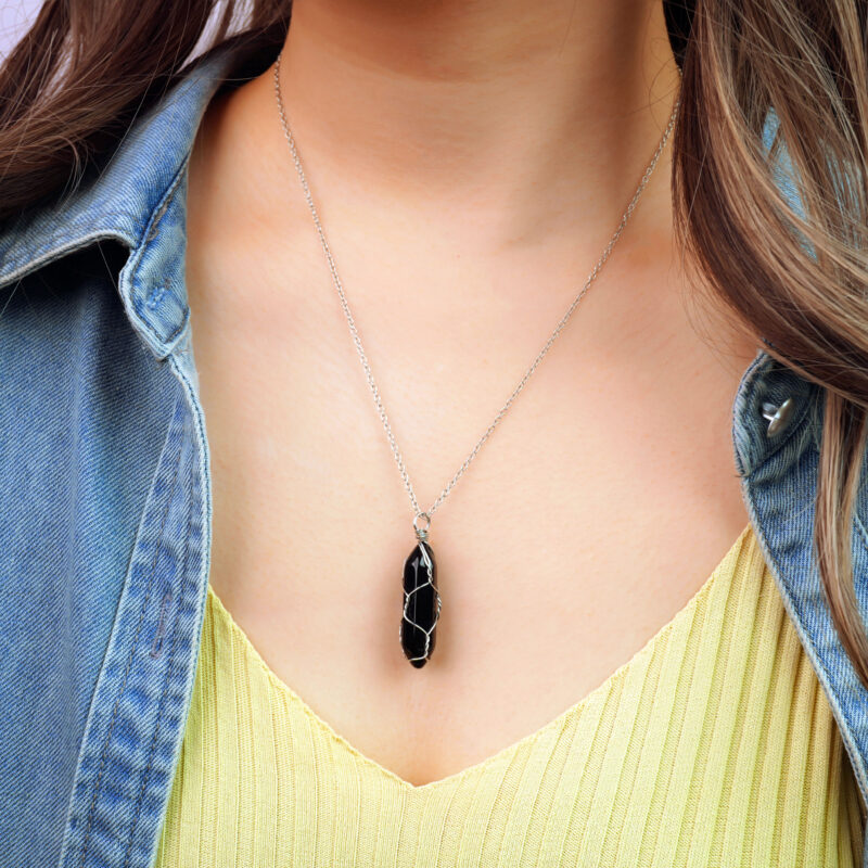 Model wearing obsidian point pendant, crystal hanging at chest level