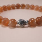 Close-up of smooth 6mm peach moonstone beads and charm detail