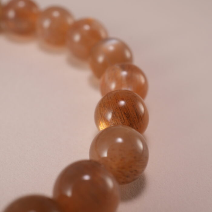 Close-up of smooth 6mm peach moonstone beads and charm detail