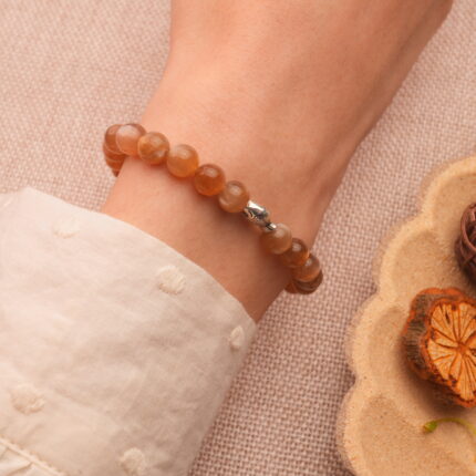 Peach moonstone bracelet worn on wrist, showing subtle glow and charm