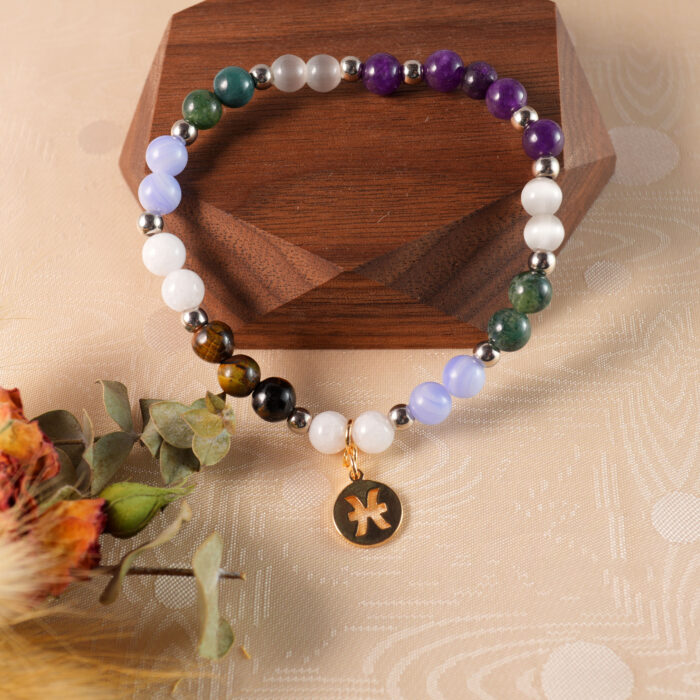 Pisces jewelry bracelet displayed on rustic wooden surface