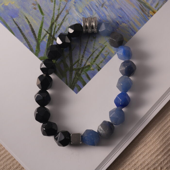 Bracelet resting beside natural stones and a soft light source, evoking calm and earthiness.