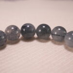 Close-up of gray agate and rutile quartz beads, showing clarity and inclusions.