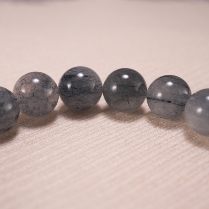 Close-up of gray agate and rutile quartz beads, showing clarity and inclusions.